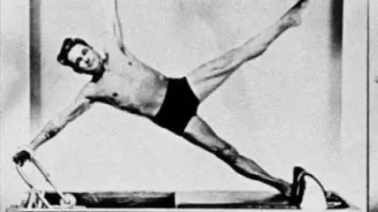 Joseph Pilates ćwiczący na reformerze wykonujący ćwiczenie “star”.